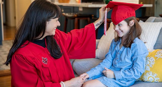 Student in graduation gown with daughter